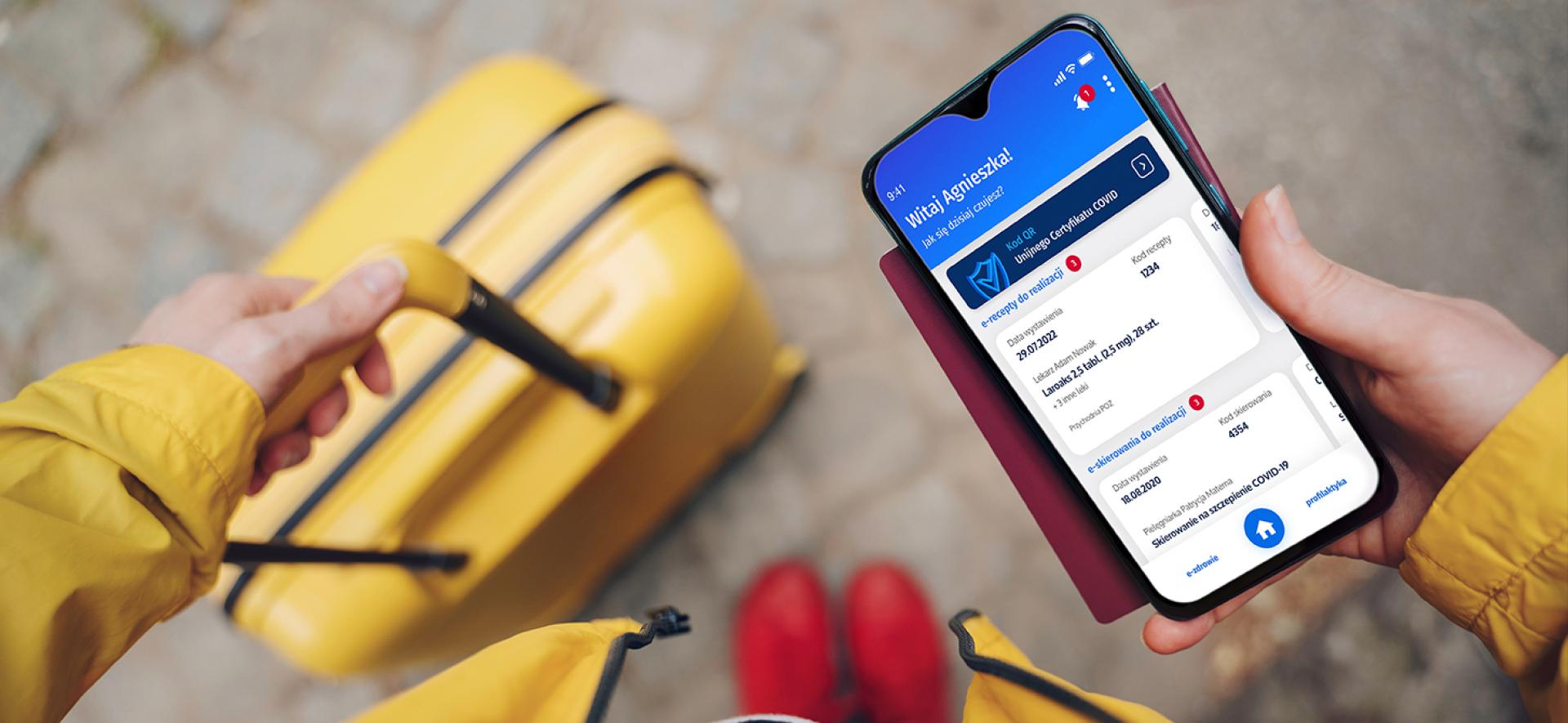 Osoba z walizką patrzącą w ekran telefonu