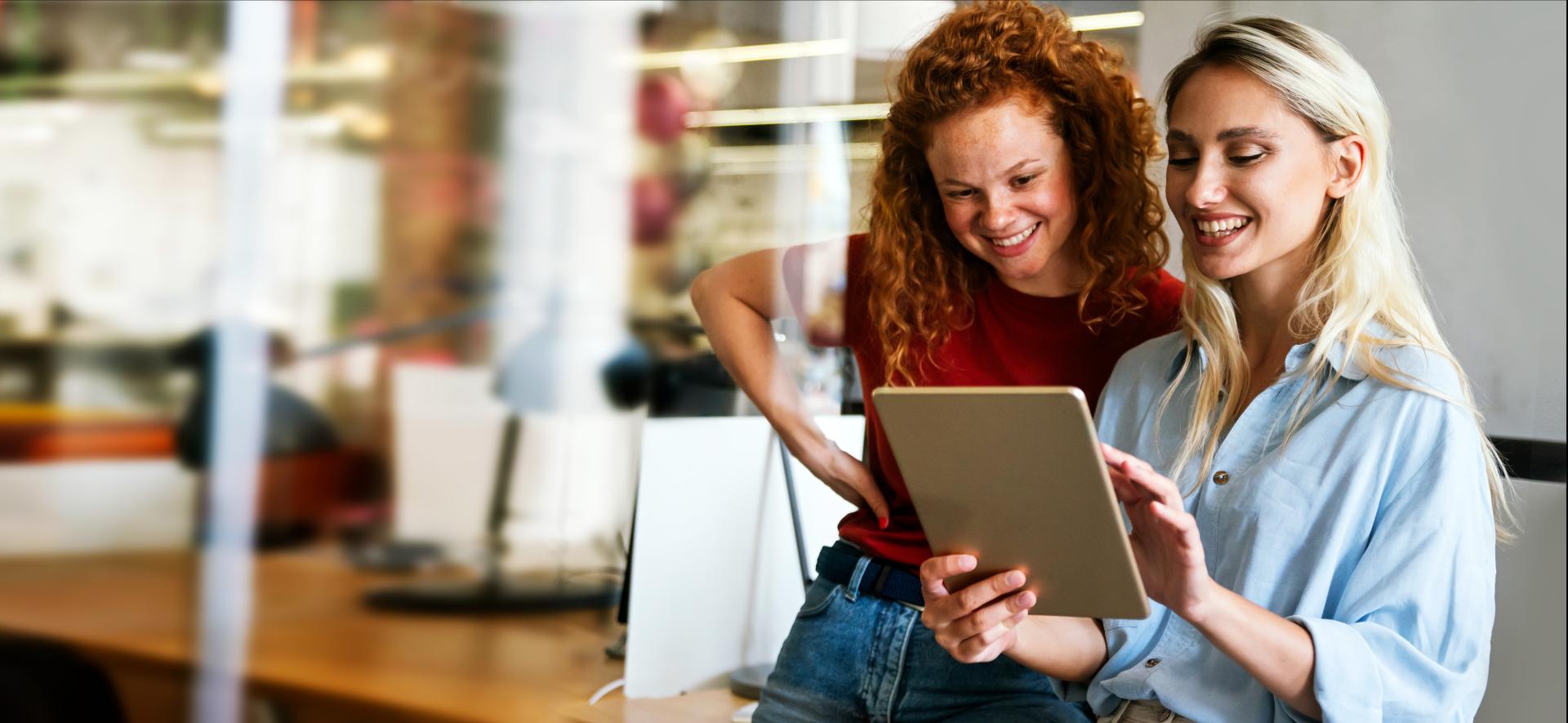 zdjęcie przedstawia dwie kobiety patrzące na ekran tabletu