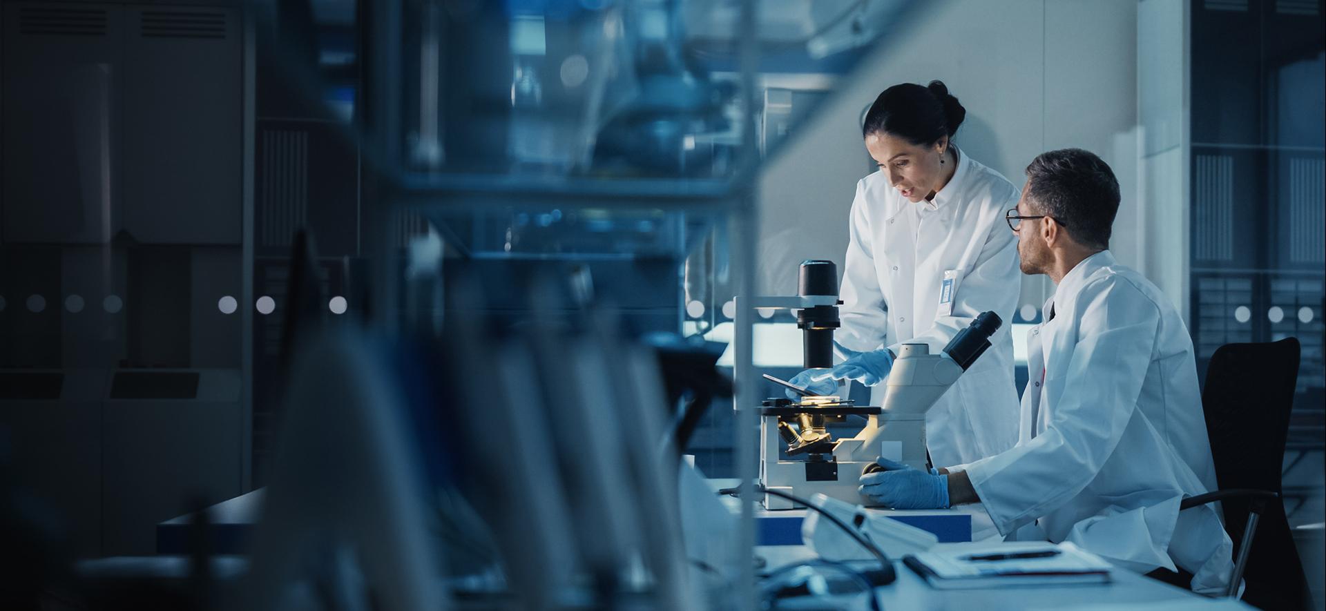 Dwoje diagnostów laboratoryjnych pracujących przy aparaturze