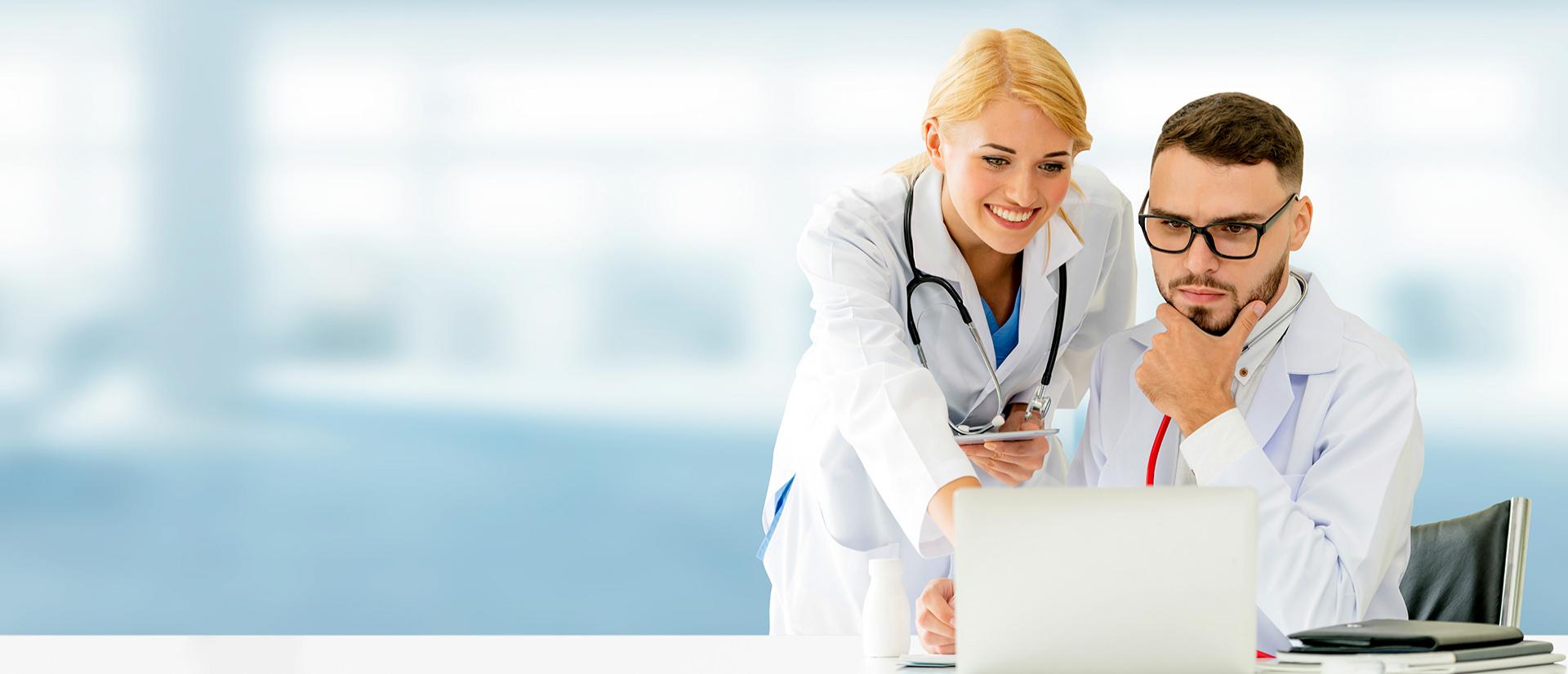 Pracownica medyczna wskazująca ekran komputera pracownikowi medycznemu