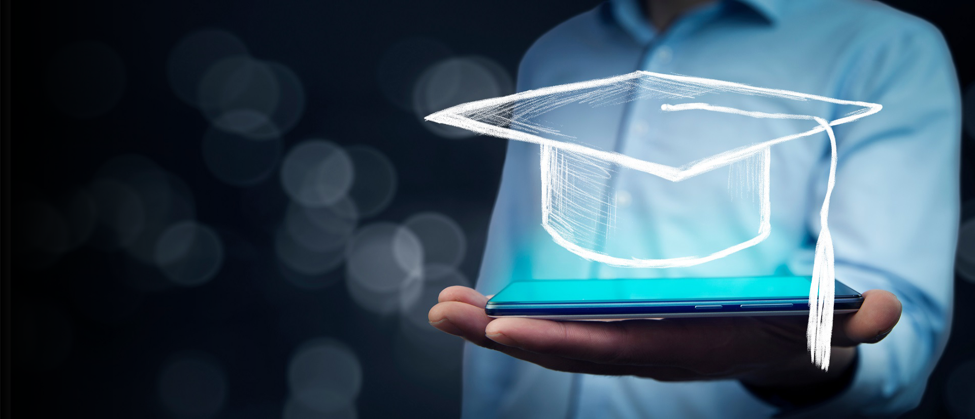 Man holding tablet with graduation cap on bokeh background