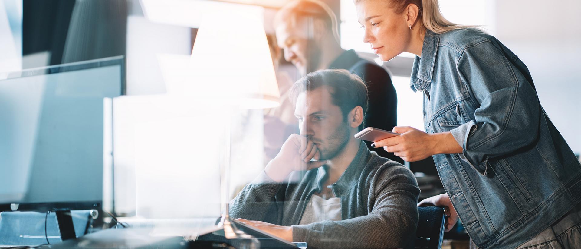 Grupa osób stojąca przy komputerze i patrząca na jego ekran