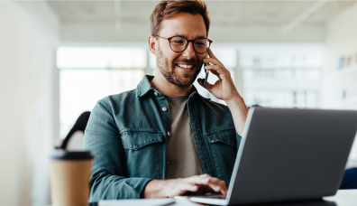 pracownik rozmawiający przez telefon przy komputerze