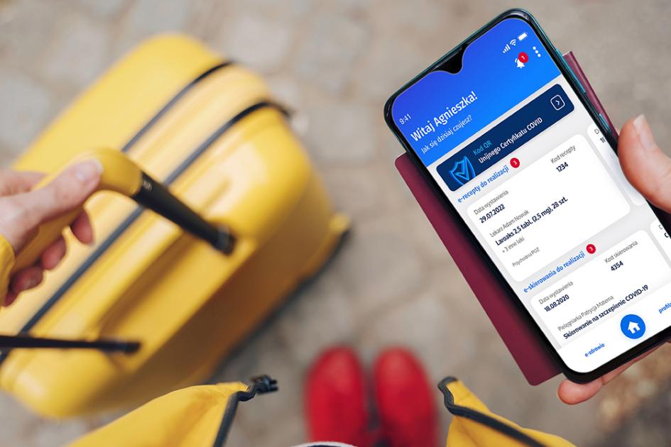 Osoba z walizką patrzącą w ekran telefonu